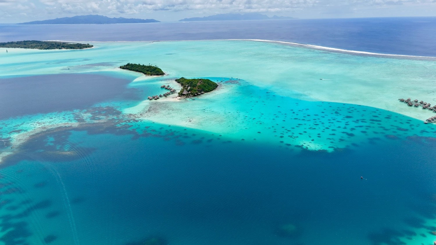 Real aerial photograph of Bora Bora's turquoise lagoon, reef and green islands